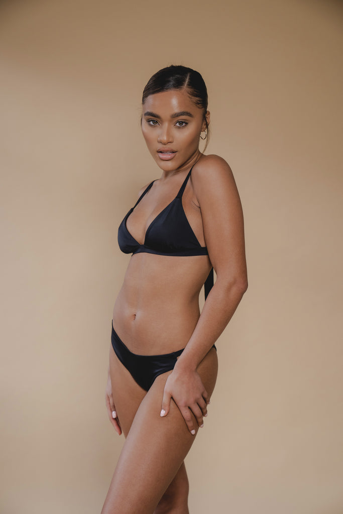 jua june sustainable swimwear. a black triangle bikini top combined with a black high leg bikini bottom. made of ecofriendly materials, high quality swimwear. luxury swimwear.