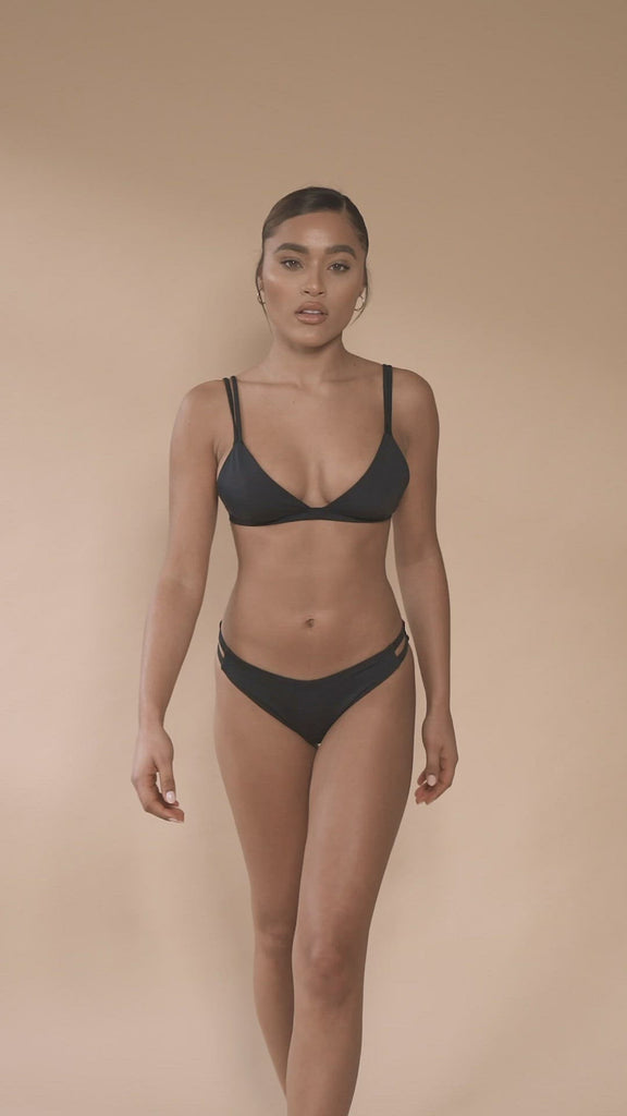 jua june sustainable swimwear. a black triangle bikini top combined with a black high leg bikini bottom. made of ecofriendly materials, high quality swimwear. luxury swimwear.